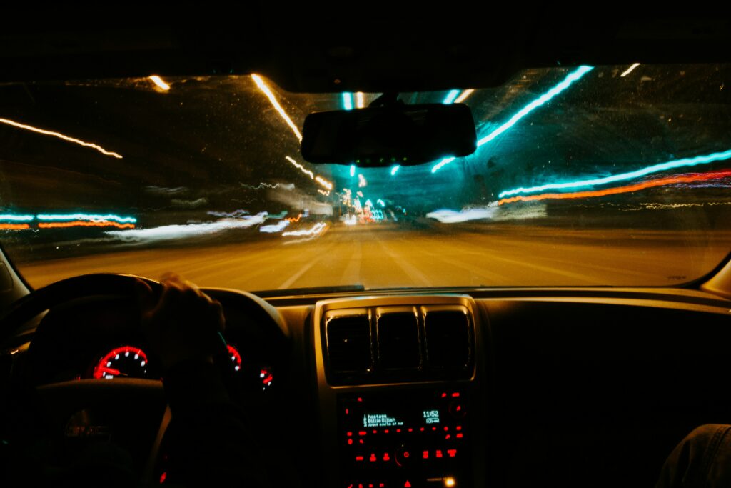 A nighttime view from inside a car, where streetlights appear as streaks or glare, indicating difficulty with night driving