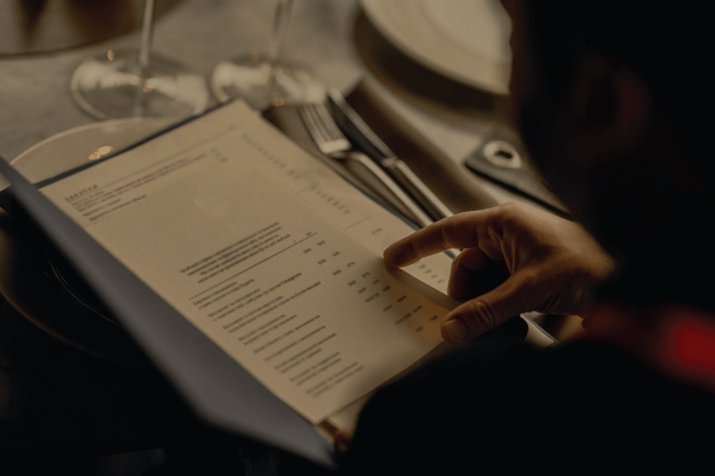 A person in a restaurant looking at a menu, struggling to read in dim lighting