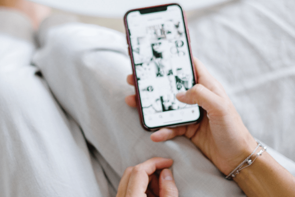 A person holding a phone at arm’s length, struggling to read the blurred screen due to blurry vision