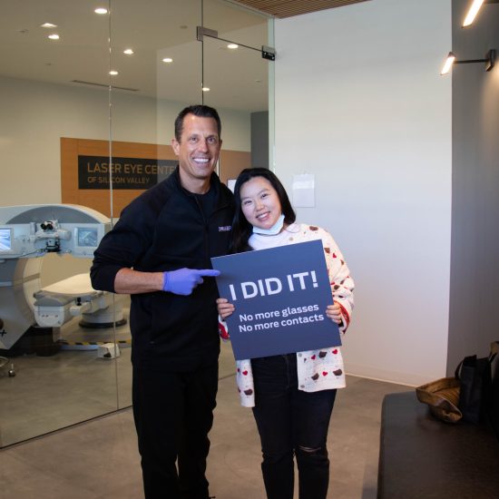 Dr. Bindi, M.D. and female patient. Short dark hair with a ivory sweater and holding an "I did it!" sign