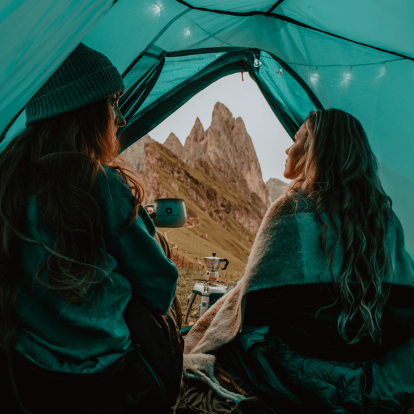 two Female Patients at Laser Eye Center of Silicon Valley with long hair having a conversation in a tent overlooking mountains